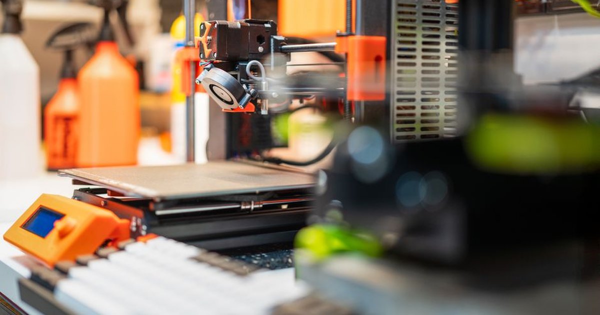 Detailed view of a 3D printer in a busy workshop, showcasing modern 3D printing technology and equipment.