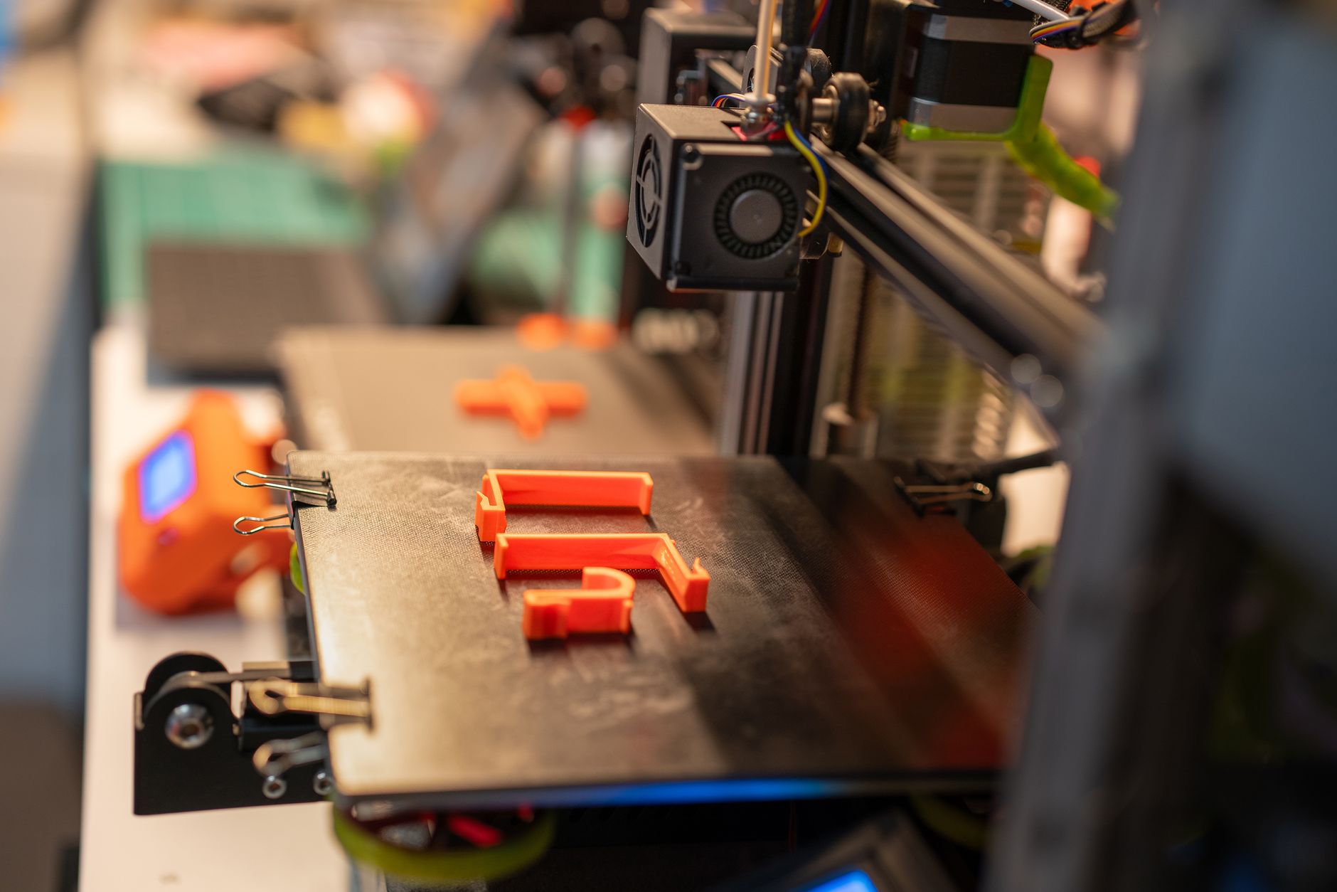 A variety of colorful filament spools and tools organized on a workshop shelf, ideal for 3D printing enthusiasts.