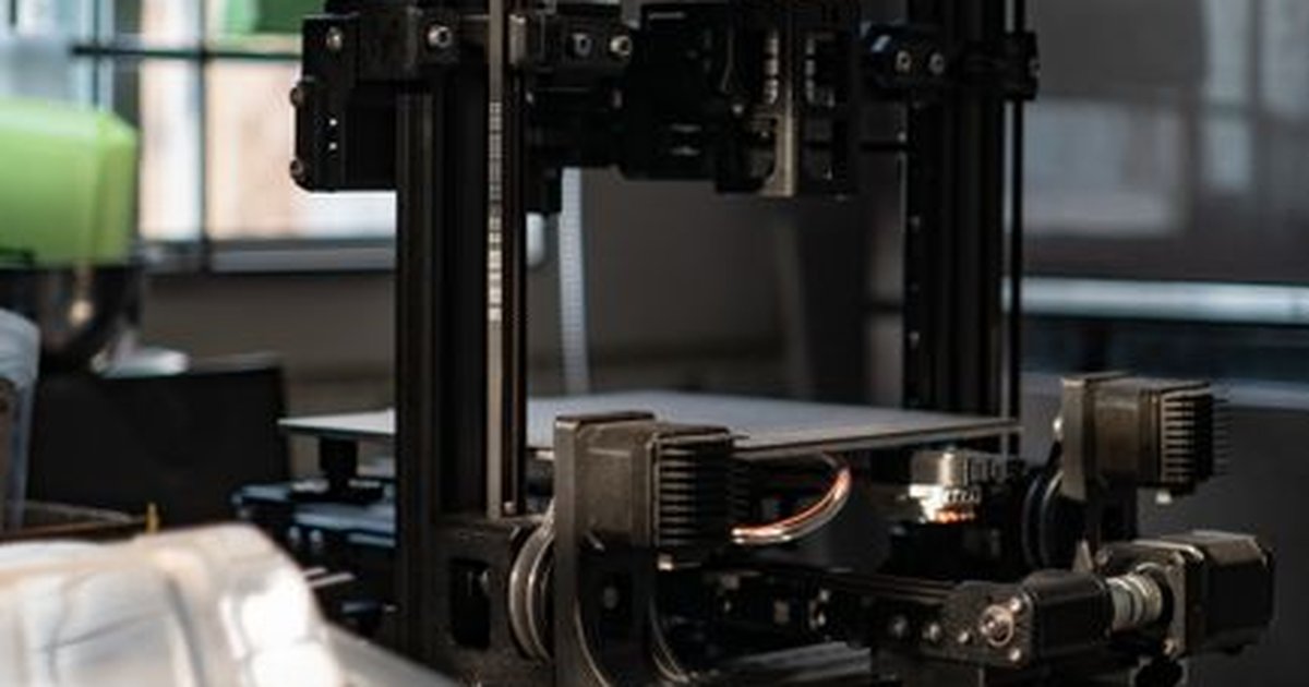 A detailed view of a 3D printer in a workshop with ambient light.