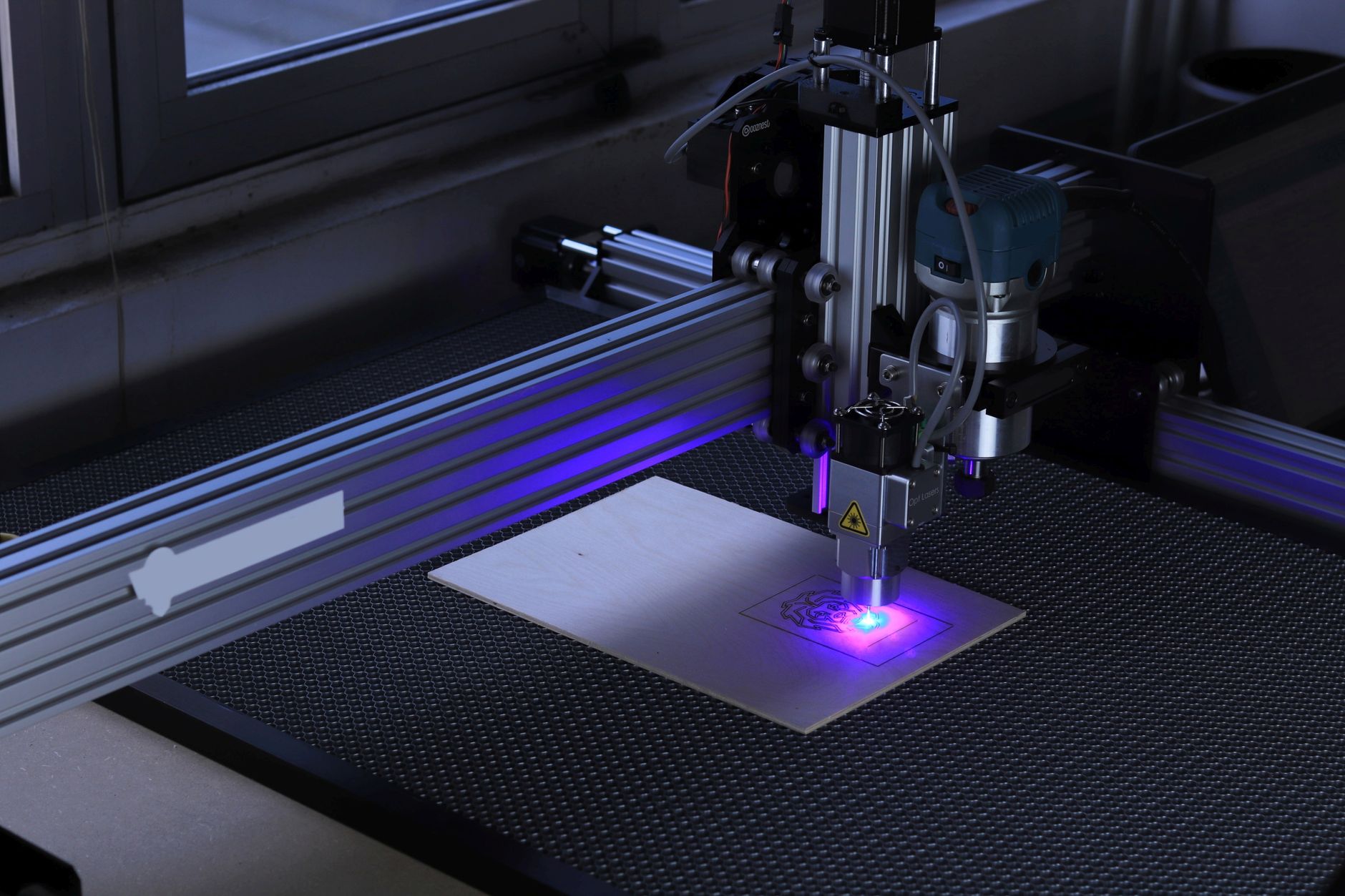 Laser engraving machine etching a wooden board in a workshop