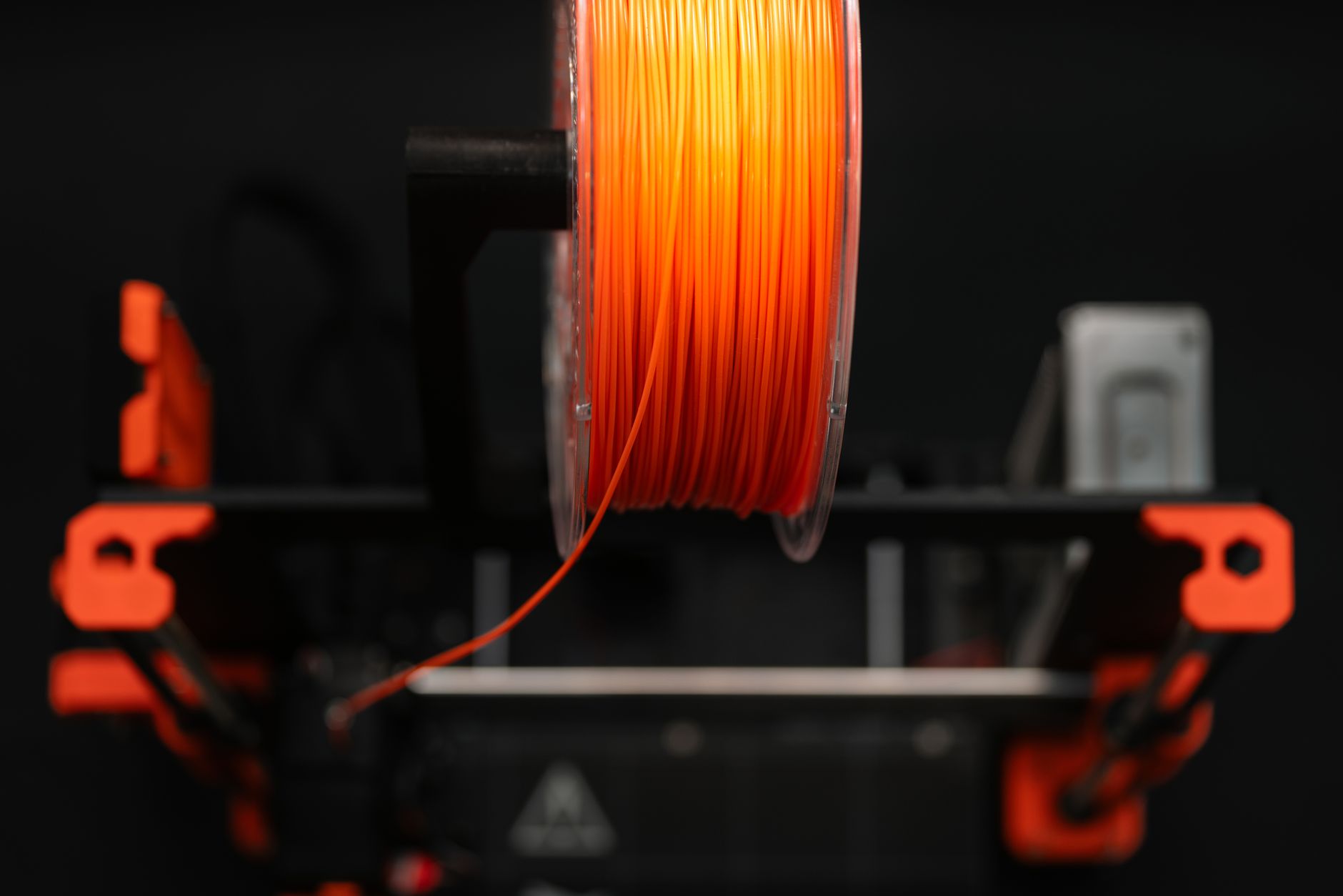 Detailed view of a 3D printer with filament and tools in a workshop setting.