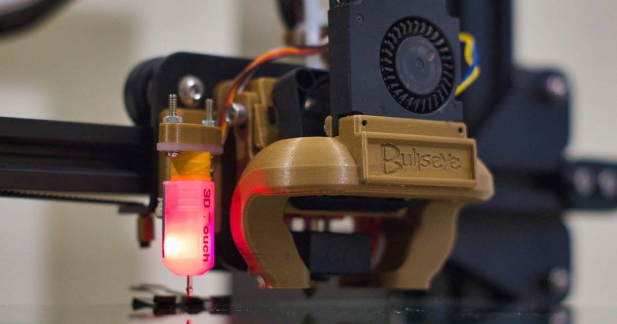Detailed shot of a 3D printer nozzle operating in a workshop setting.