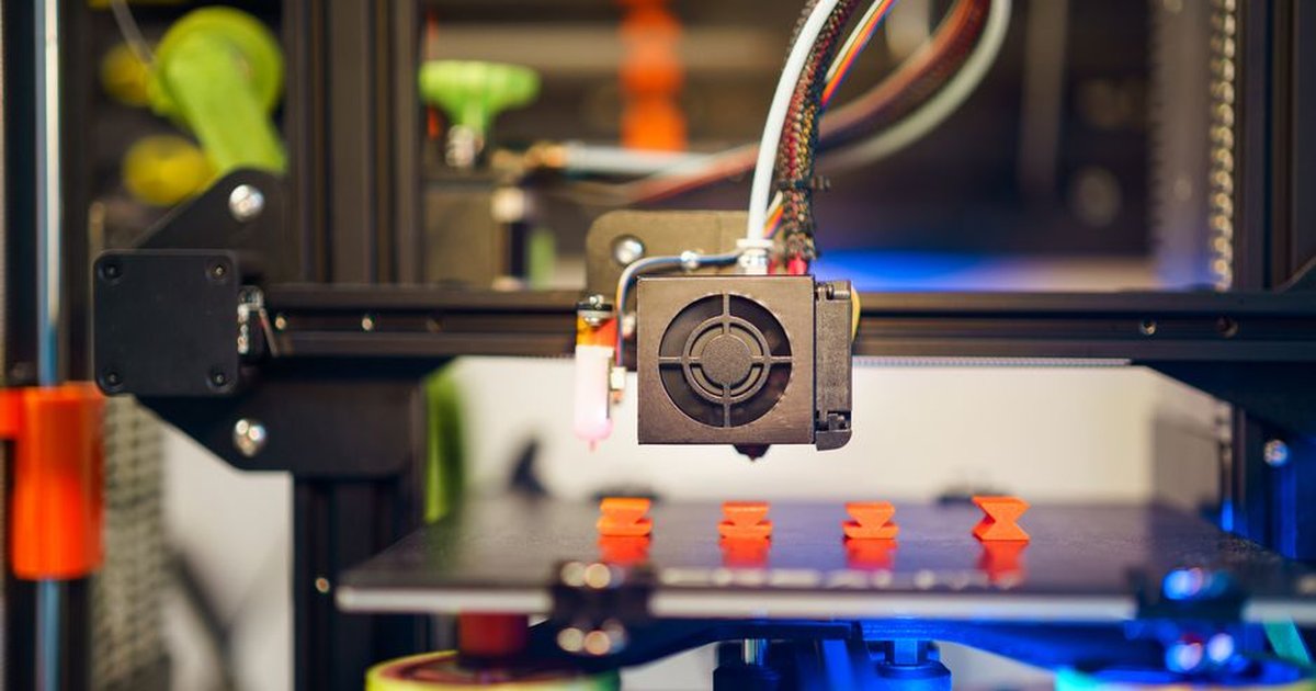 Detailed view of a 3D printer in action, fabricating small plastic pieces indoors.
