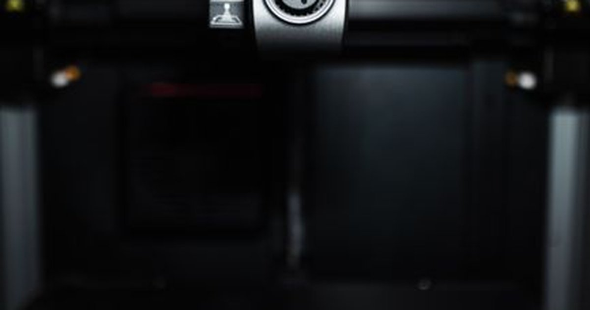 Close-up of a high-precision industrial 3D printer nozzle in a dark setting, showcasing advanced technology.