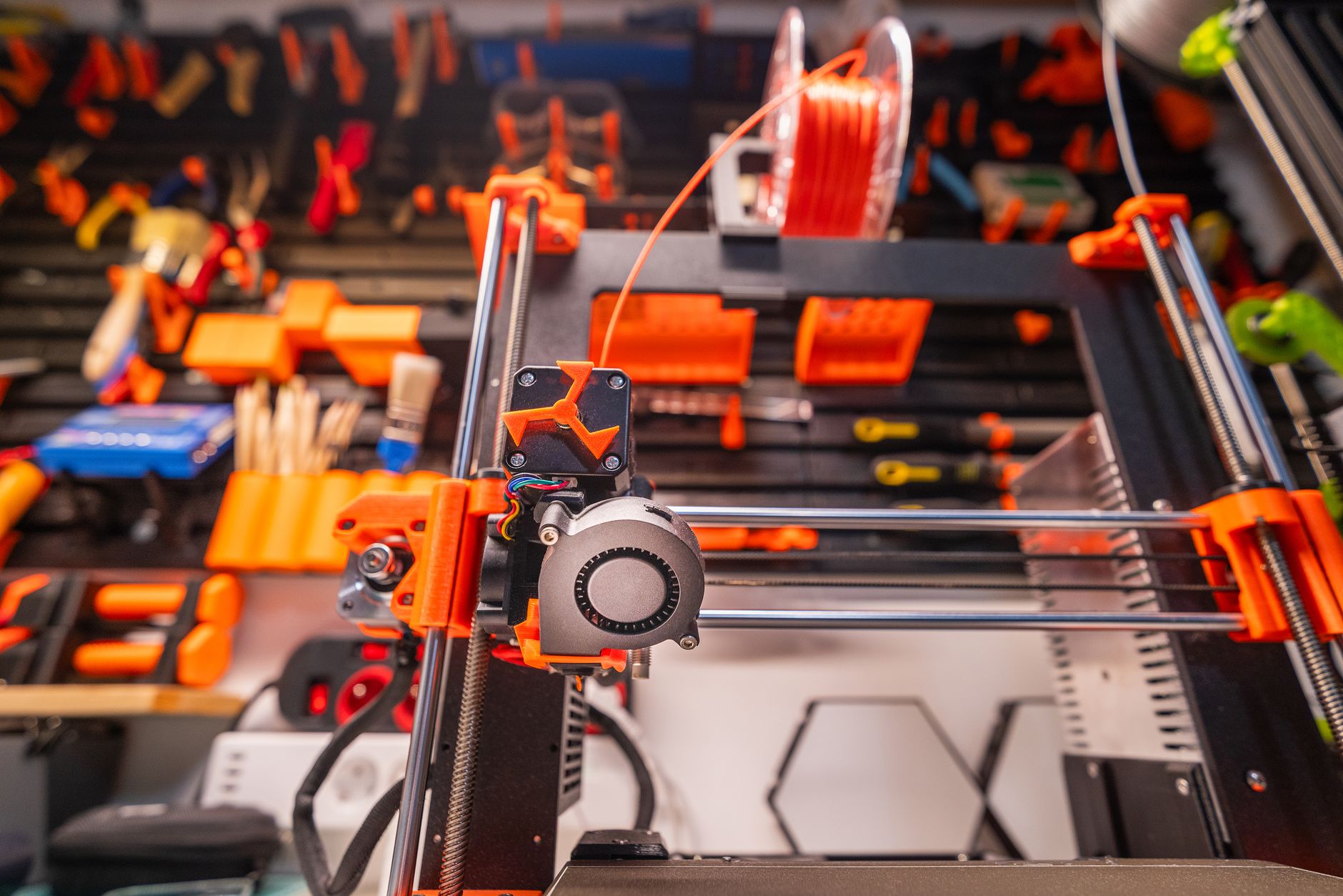 A close-up of a modern 3D printer in action, illuminated by vibrant, colorful lighting indoors.