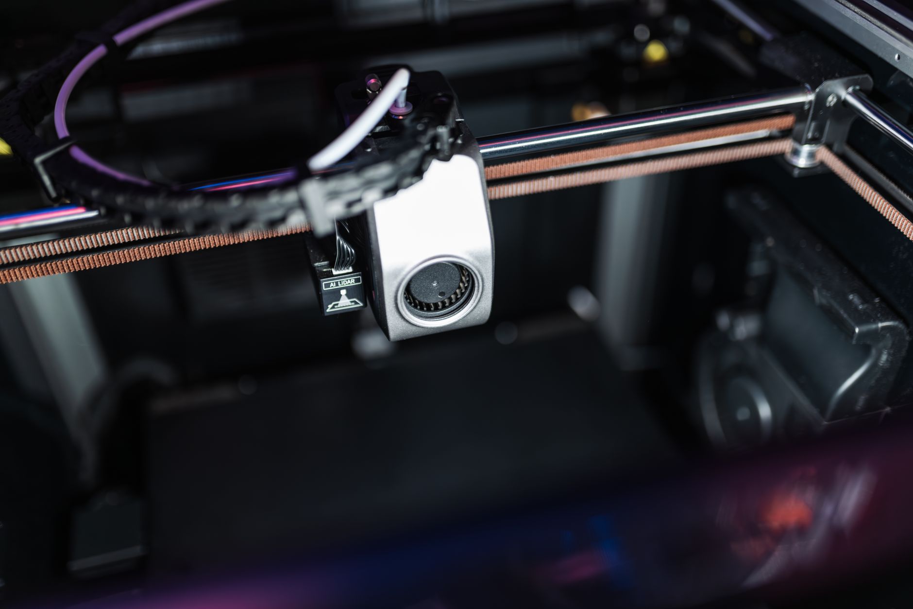 Close-up of a modern 3D printer in a workshop, highlighted by neon lighting.