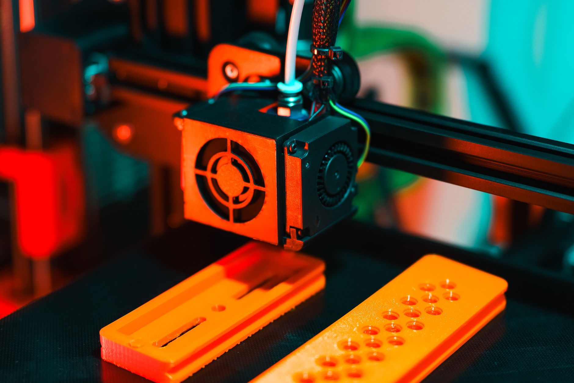 Close-up of a 3D printer and printed parts in a modern workshop setting.