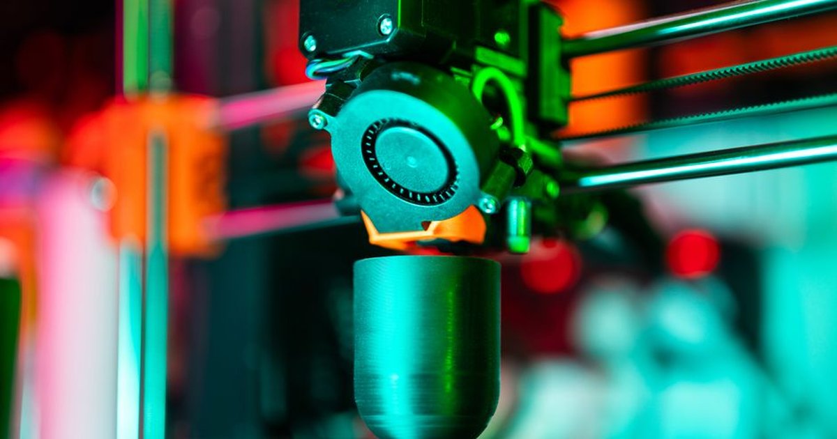 Close-up of a 3D printer creating a product in neon lighting.