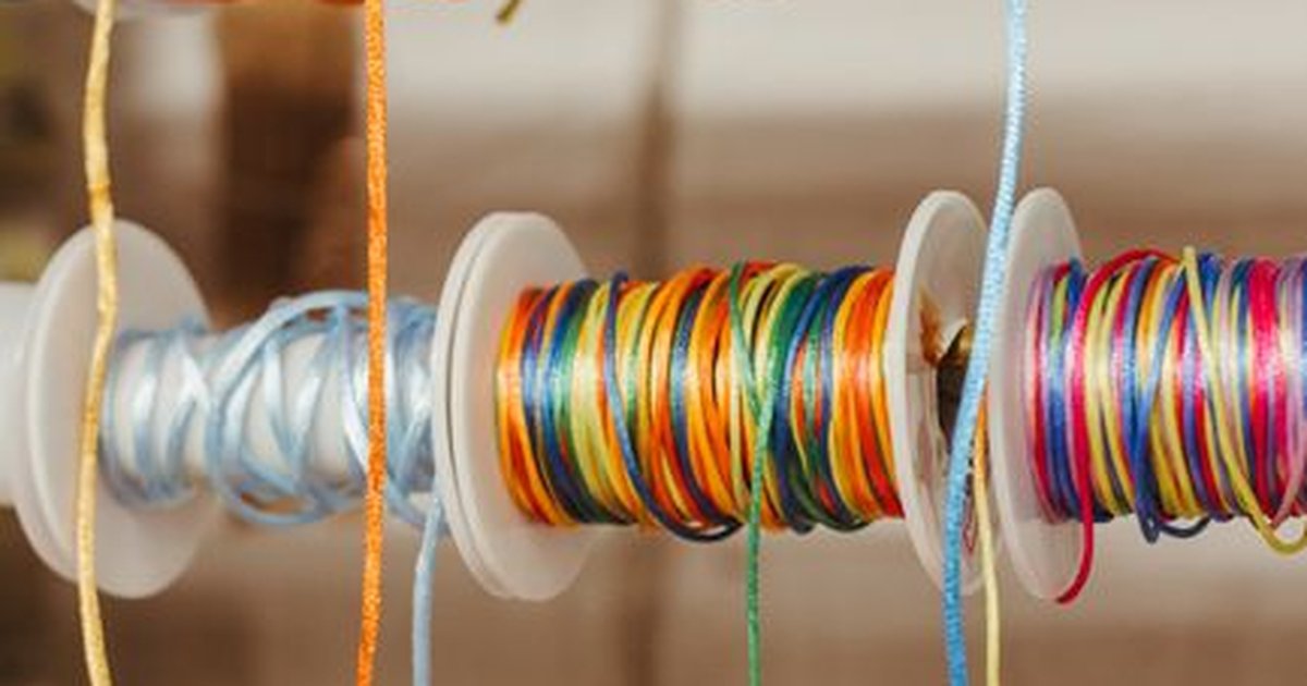 Vibrant multi-colored spools of thread neatly arranged in a sewing store display for crafting projects.